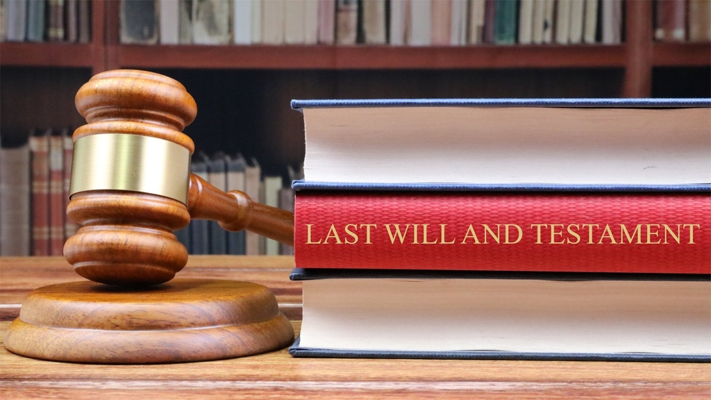 Gavel and stacked red-spined book titled “LAST WILL AND TESTAMENT” on a wooden table.
